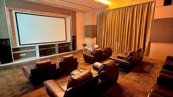 A home theater with a large screen, leather seating, and a patterned carpet.
