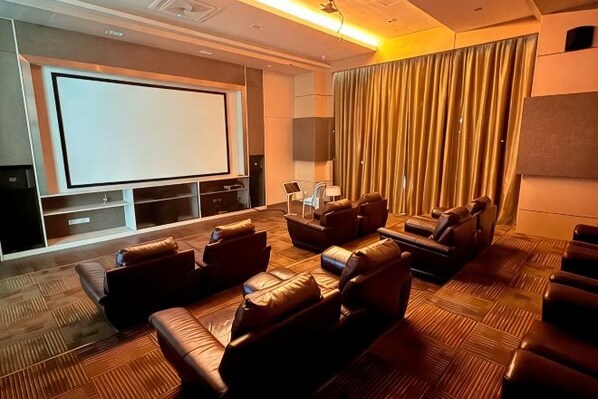 Un cine en casa con una pantalla grande, asientos de cuero y una alfombra estampada.