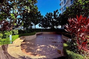 A landscaped outdoor area with a curved seating area, surrounded by trees and shrubs. - Macrolink 2B2R 7 pax Condo Medini near legoland (Iskandar Puteri)