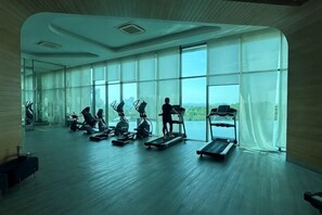 A gym with cardio machines, a treadmill, and large windows. - Macrolink 2B2R 7 pax Condo Medini near legoland (Iskandar Puteri)