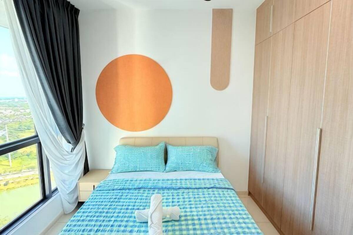 A bedroom with a bed, a large window, a wardrobe, and a circular wall decoration.