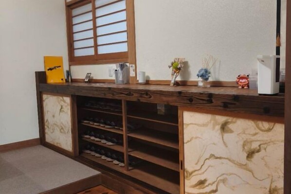 Una encimera de madera con un zapatero integrado y una ventana con listones de madera.
