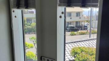 Una ventana con vista a una calle, un edificio y un coche estacionado.