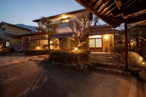 Una casa tradicional japonesa con estructura de madera, un sendero de piedra y un jardín bien cuidado.