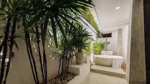 A modern bathroom with a bathtub, a sink, and a shower area. There are plants and a small seating area. - Balinese 2 Bedroom Private Pool Villa (Kbr11) (Koh Samui)