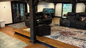 Un salón amplio con piso de madera, dos sofás de cuero, un acuario de vidrio y vistas al exterior.