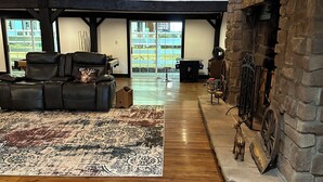 Un salón amplio con un gran sofá de cuero, una alfombra estampada y una chimenea de piedra.