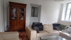 Un saló amb un sofà beix, una taula de cafè de vidre, un armari de fusta i una porta.