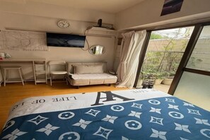 A bedroom with a bed, a desk, a chair, a sofa, a TV, and a window with a view. - Tokyo Harbor (Tokyo)