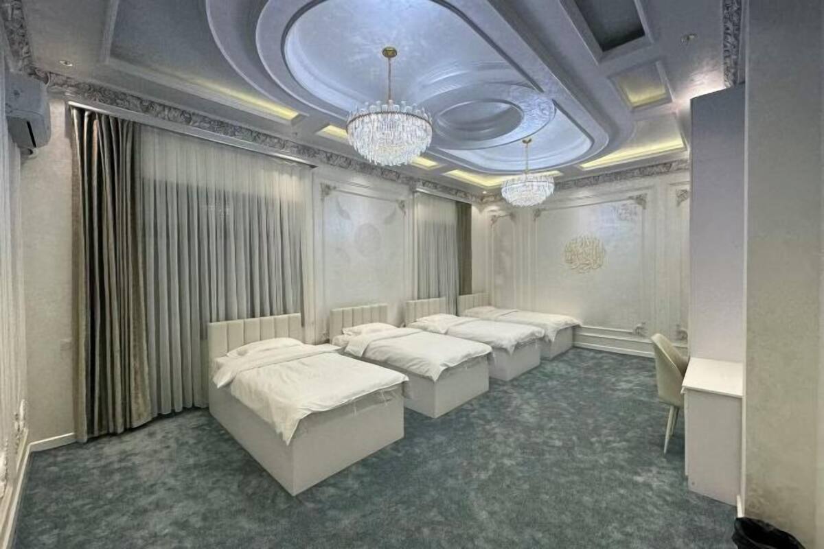 Ein Hotelzimmer mit drei Betten, einem Schreibtisch und einer Kandelaber.