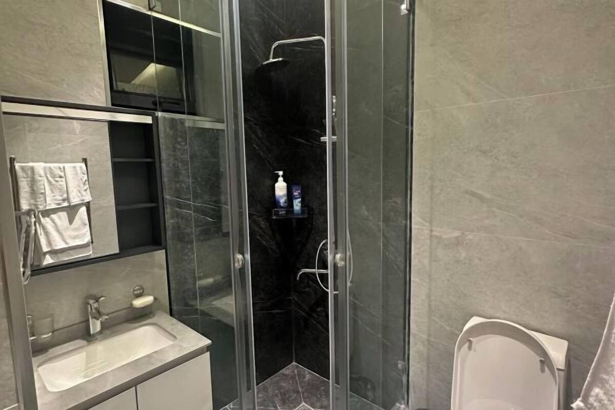 Ein modernes Badezimmer mit einer Glasdusche, einem Waschbecken mit Spiegel und einer Toilette.
