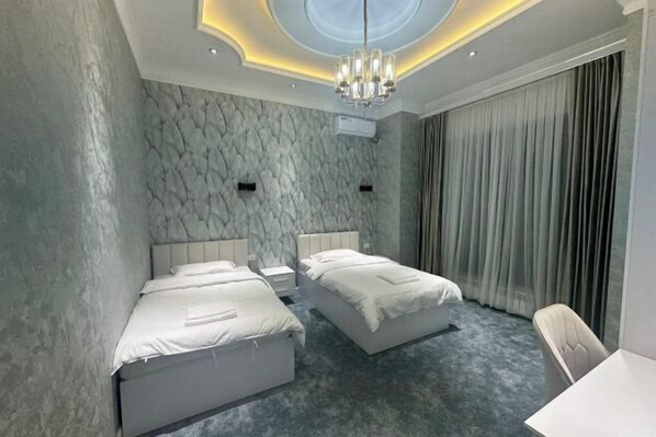A modern hotel room with two beds, a chandelier, and a large window with curtains. - yuelai hotel (Tashkent)