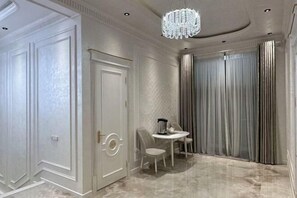 A room with a marble floor, a chandelier, a table with chairs, and a door with a circular handle. - yuelai hotel (Tashkent)