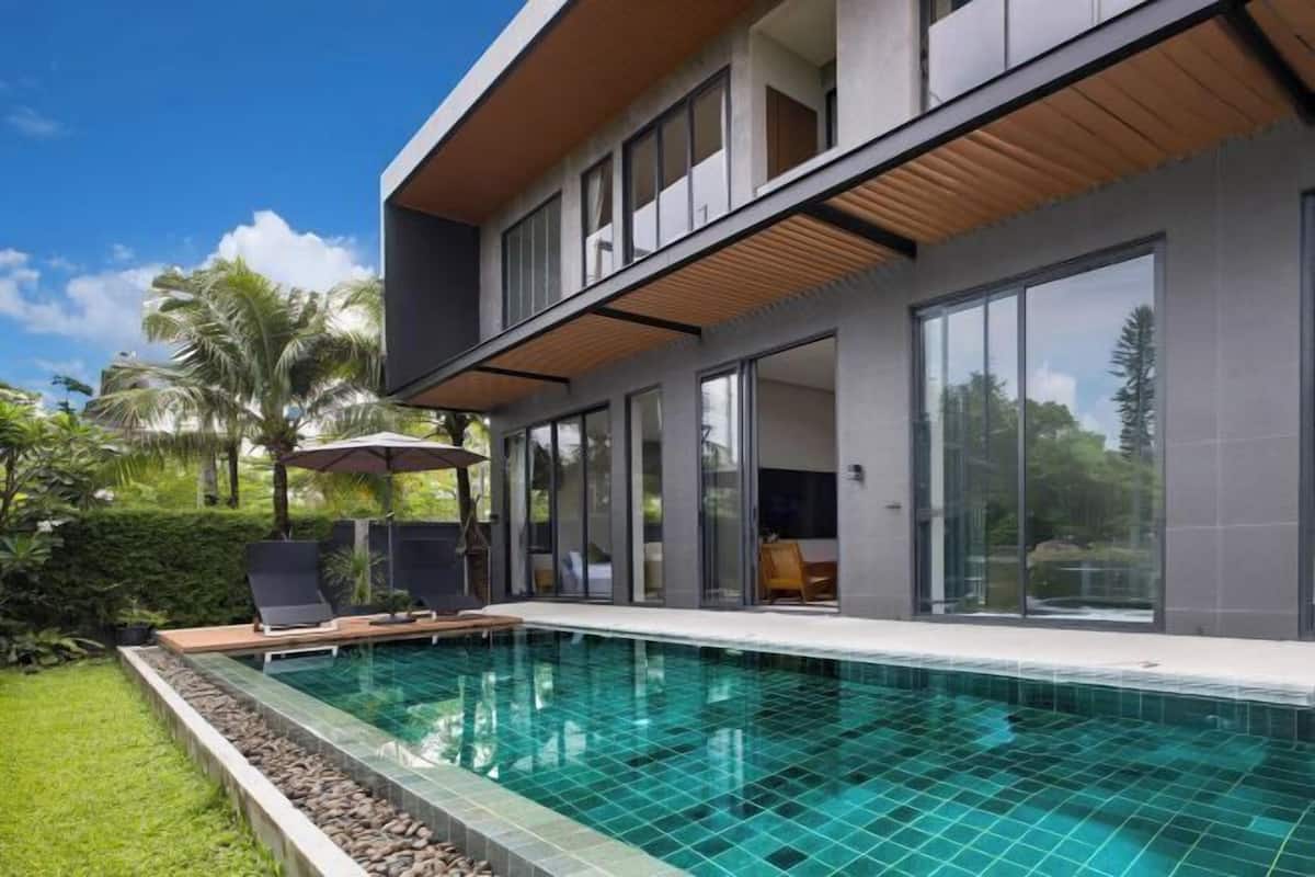 Una casa moderna con piscina, ampie finestre e un giardino curato.
