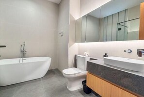 Un baño moderno con una bañera independiente, un inodoro y un tocador con espejo.