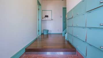A hallway with lockers, a trash bin, and a shelf with a mirror.