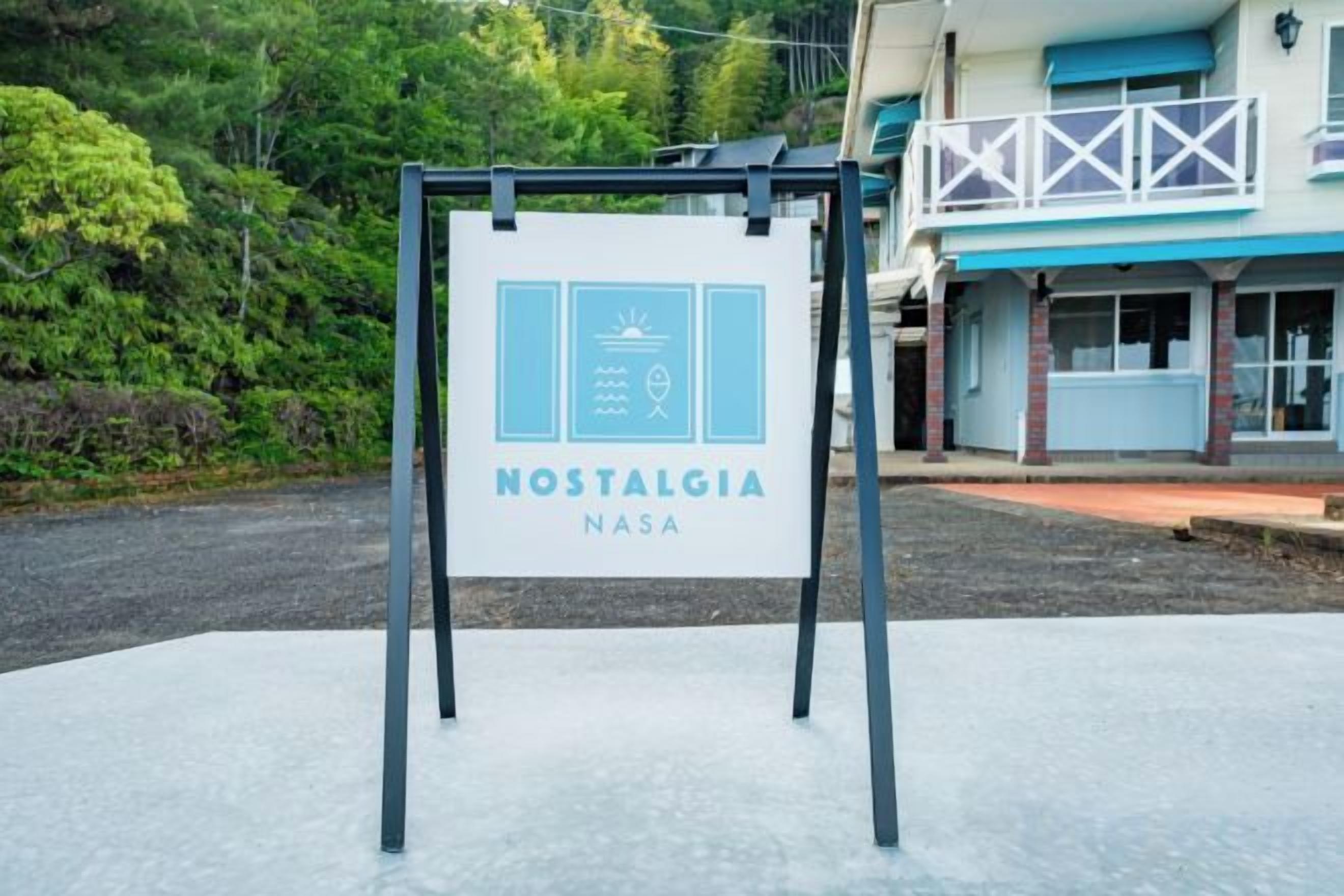 A signboard for 'Nostalgia NASA' with a clear view of the surrounding area including a building with a balcony.