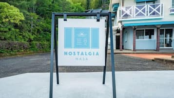 A signboard for 'Nostalgia NASA' with a clear view of the surrounding area including a building with a balcony.