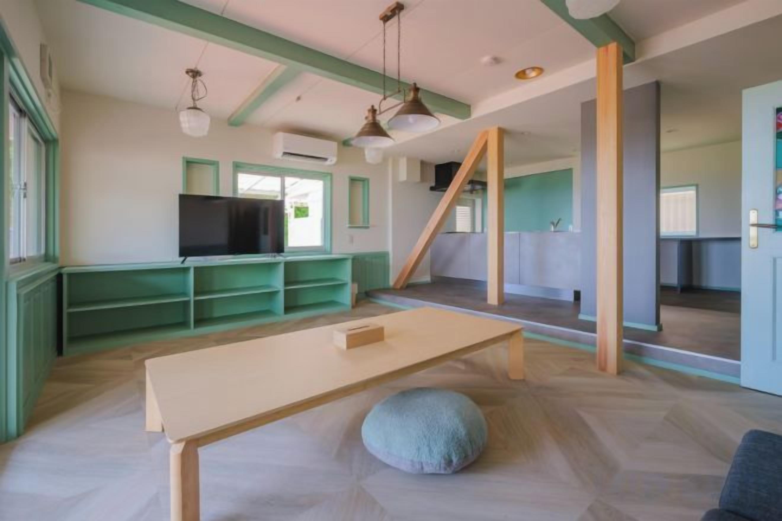 Una stanza con televisione, un tavolo di legno e un pouf.