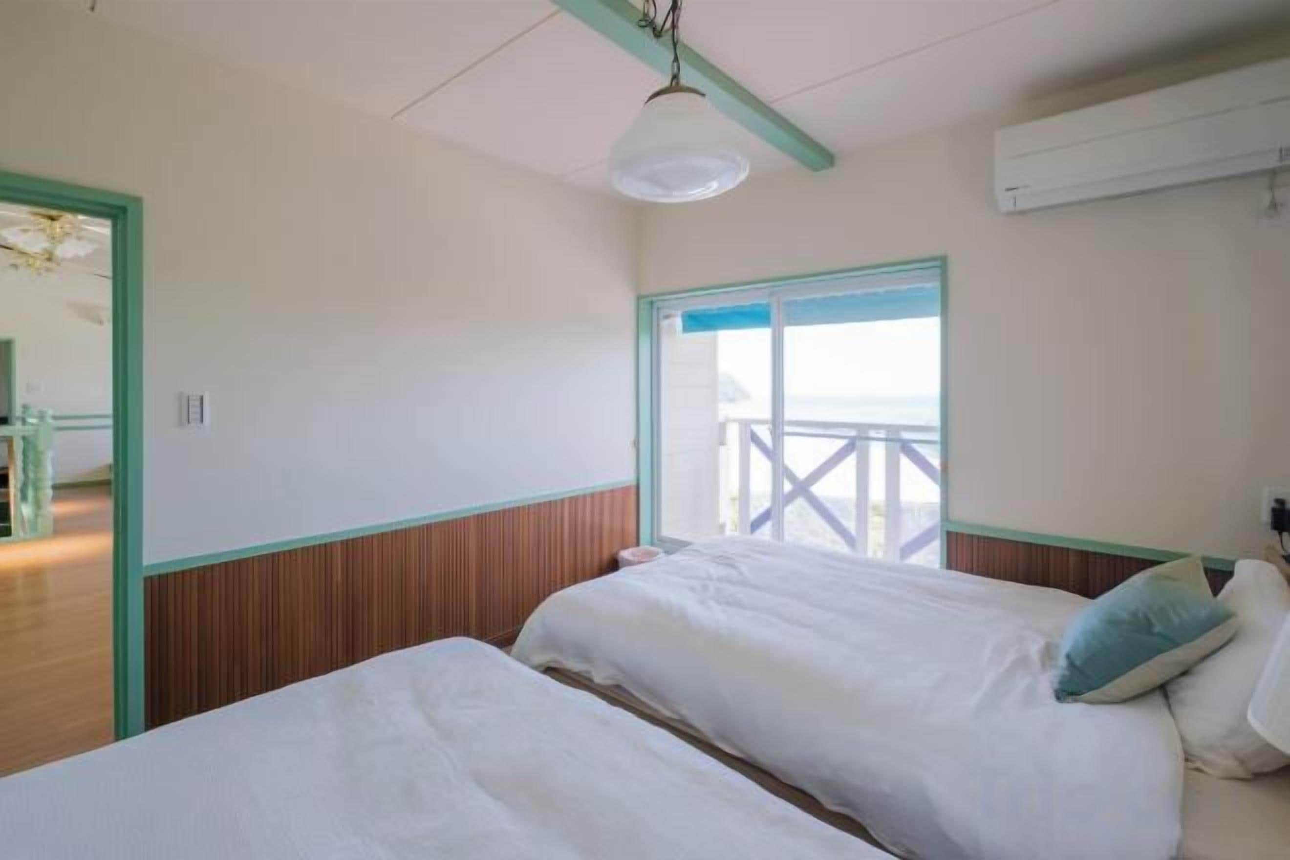 A bedroom with two beds, a window with a view, and a ceiling fan.