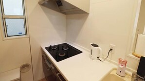 Een kleine keuken met een gasfornuis, een koffiezetapparaat en een spoelbak.