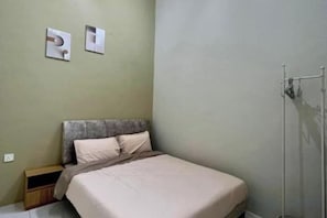 A bedroom with a bed, a nightstand, and a wall-mounted radiator. - PoloStay Landed House 4 Room for 10 pax (Ipoh)