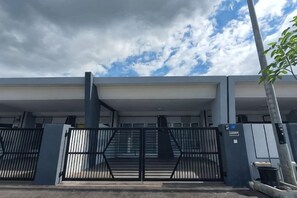 A gated entrance to a building with a covered walkway and a tree to the right. - PoloStay Landed House 4 Room for 10 pax (Ipoh)