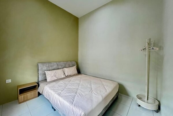 A bedroom with a bed, a bedside table, a coat rack, and a small wooden cabinet. - PoloStay Landed House 4 Room for 10 pax (Ipoh)