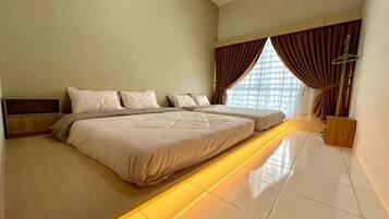 A hotel room with a large bed, a bedside table, a window with curtains, and a view of the outside.