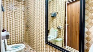 A bathroom with a toilet, shower, and a large mirror reflecting a wooden door. - The White House Kamala Phuket (Phuket)