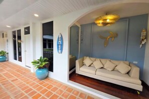 A reception area with a sofa, a blue wall with a gold decorative piece, and potted plants. - Seaside Bliss Villa Rawai (Phuket)