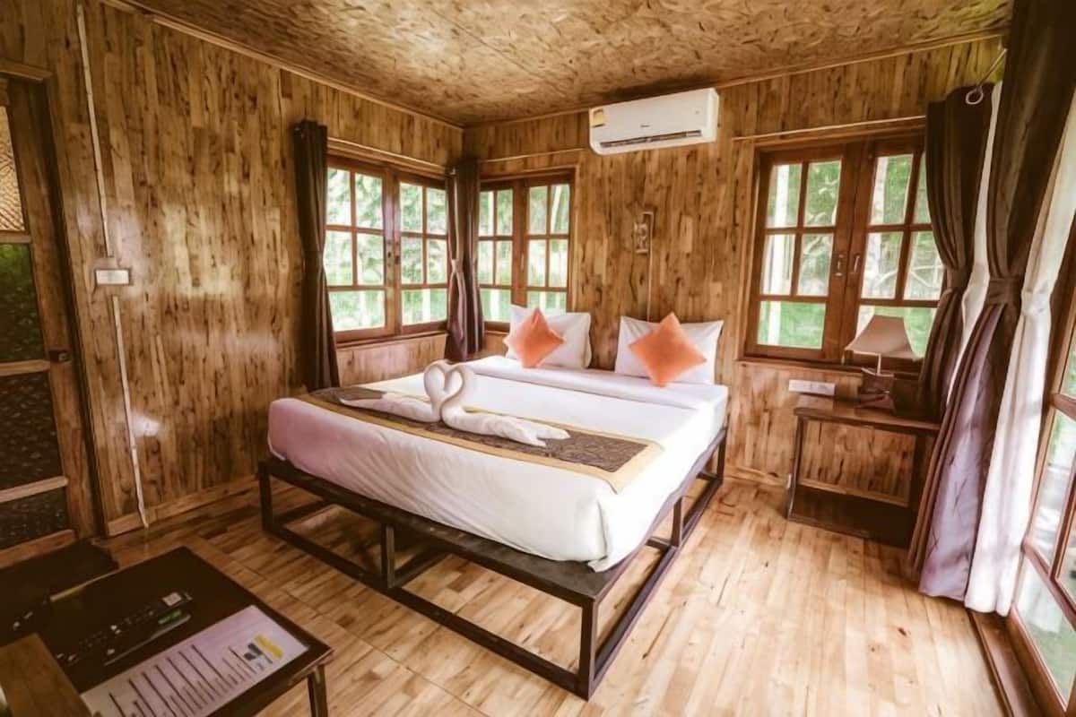 Ein Zimmer mit Holzboden, einem Bett, einem Schreibtisch und einem Fenster.