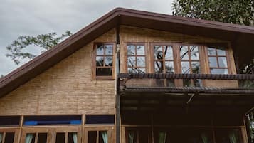 A two-story building with a sloped roof, large windows, and a balcony.