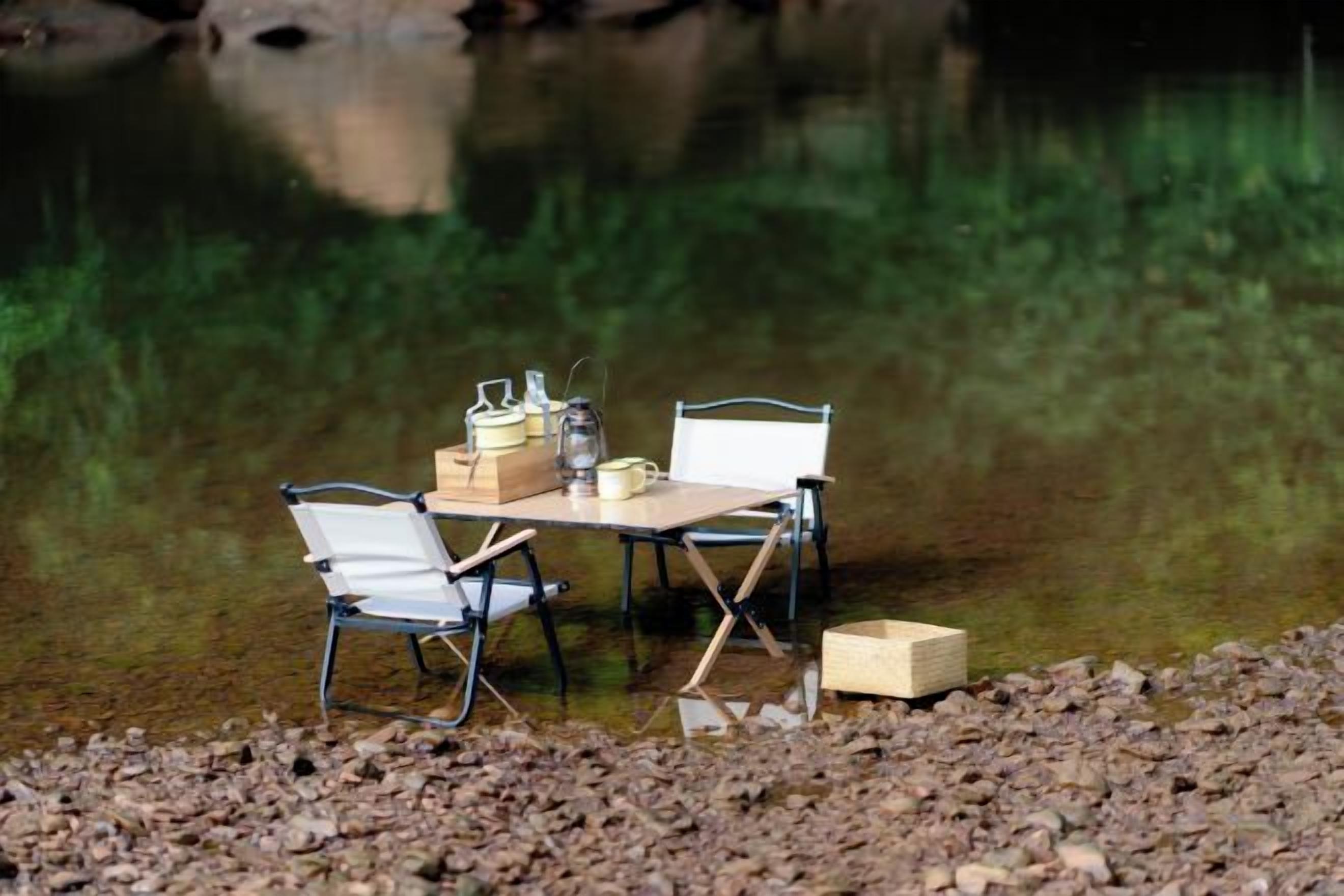 A camping setup with a table and chairs by a body of water.
