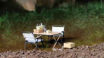 A camping setup with a table and chairs by a body of water.