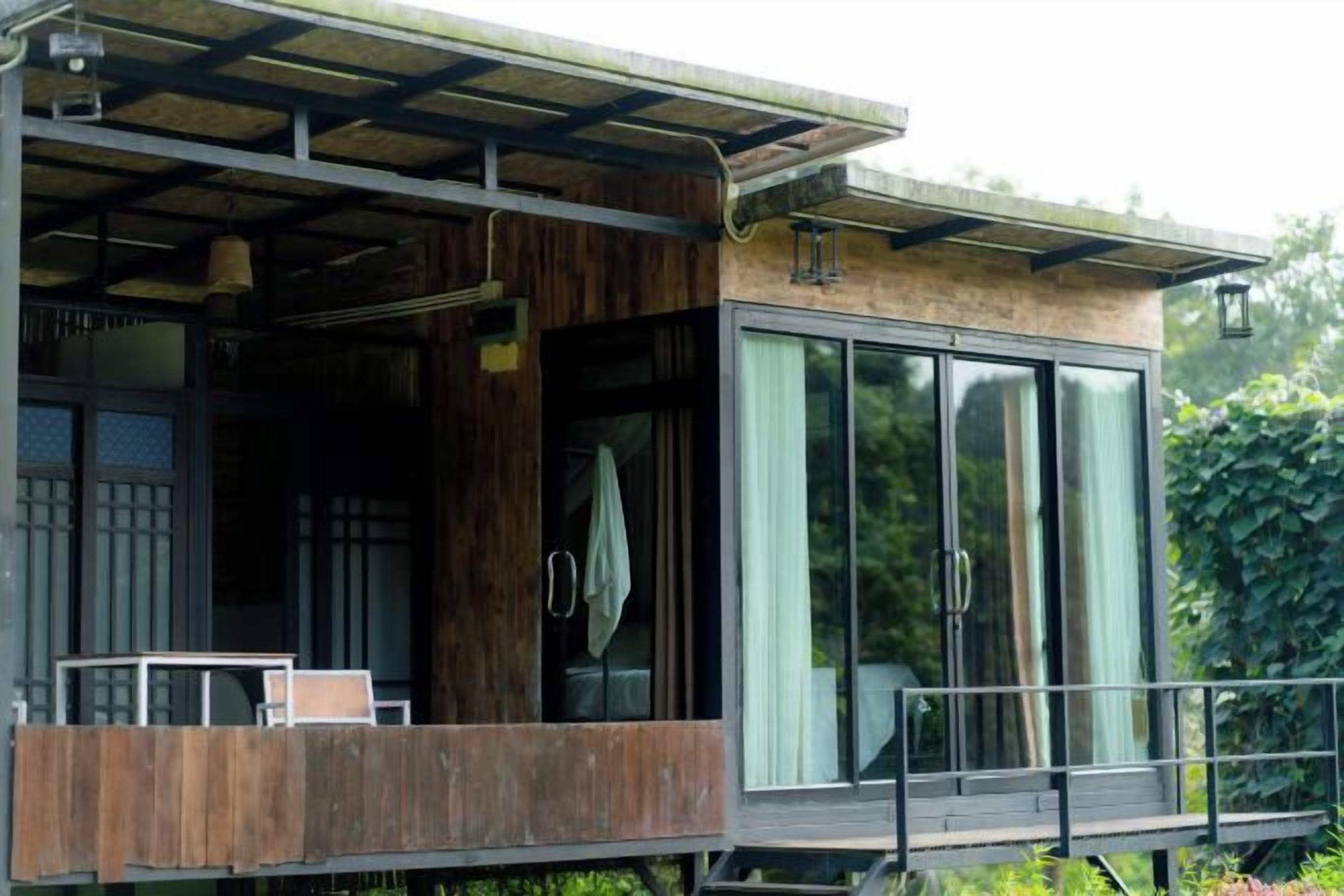 A modern building with a balcony, large windows, and a wooden exterior.