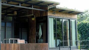 A modern building with a balcony, large windows, and a wooden exterior.