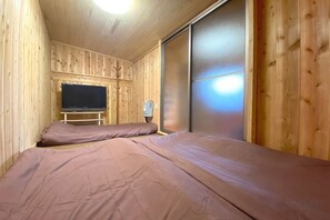 A room with two beds, a television, and a sliding door. - Pukōji Temple (Numata)