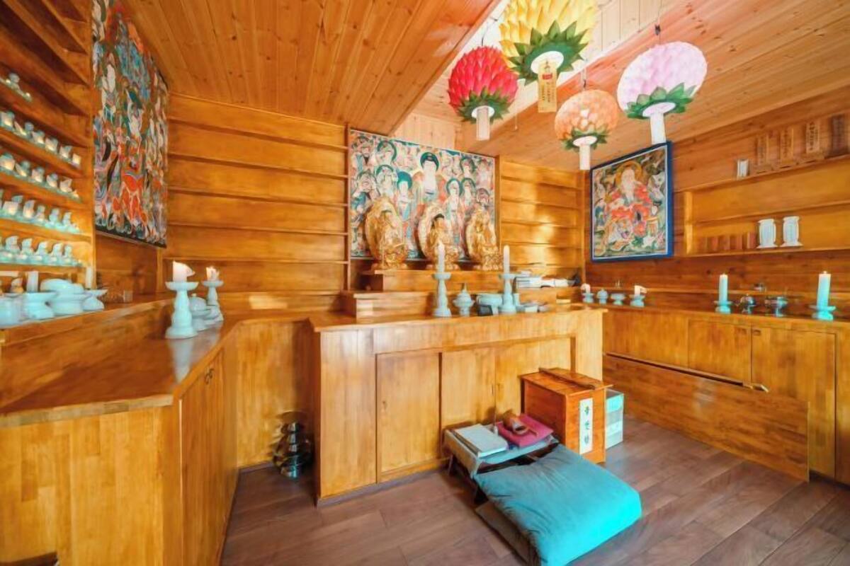Un interior de madera con un mostrador central, estanterías con objetos y obras de arte en las paredes.