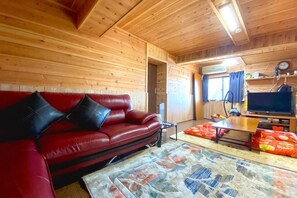 A wooden interior with a red leather sofa, a television, and a dining area. - Pukōji Temple (Numata)