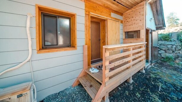 A wooden cabin with a wooden deck, a door, and a window. - Pukōji Temple (Numata)