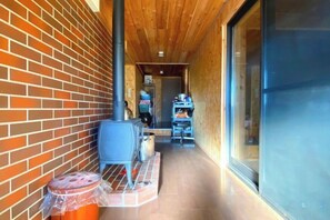 A corridor with a brick wall, a wooden ceiling, and a glass door leading to a room. - Pukōji Temple (Numata)
