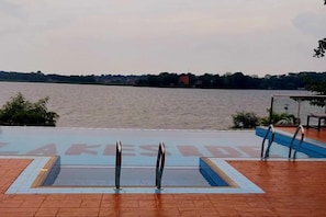 A swimming pool with a view of a body of water and a distant shoreline. - The Biira Residence (Busiro)