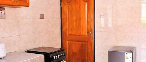 A kitchen with a wooden door, a stove, and a refrigerator.