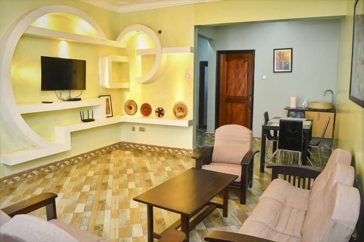 A living room with a TV, seating, a dining area, and a kitchen.