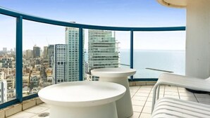 A balcony with a city view, two white round tables, and a white lounge chair. - Magnificent Seaside Panorama Stay by Sea N' Rent (Tel Aviv)