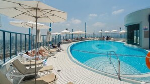 A rooftop pool with lounge chairs and umbrellas, surrounded by a high fence. - Magnificent Seaside Panorama Stay by Sea N' Rent (Tel Aviv)