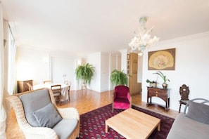 Una sala de estar con sofá, sillón, mesa de centro y plantas.
