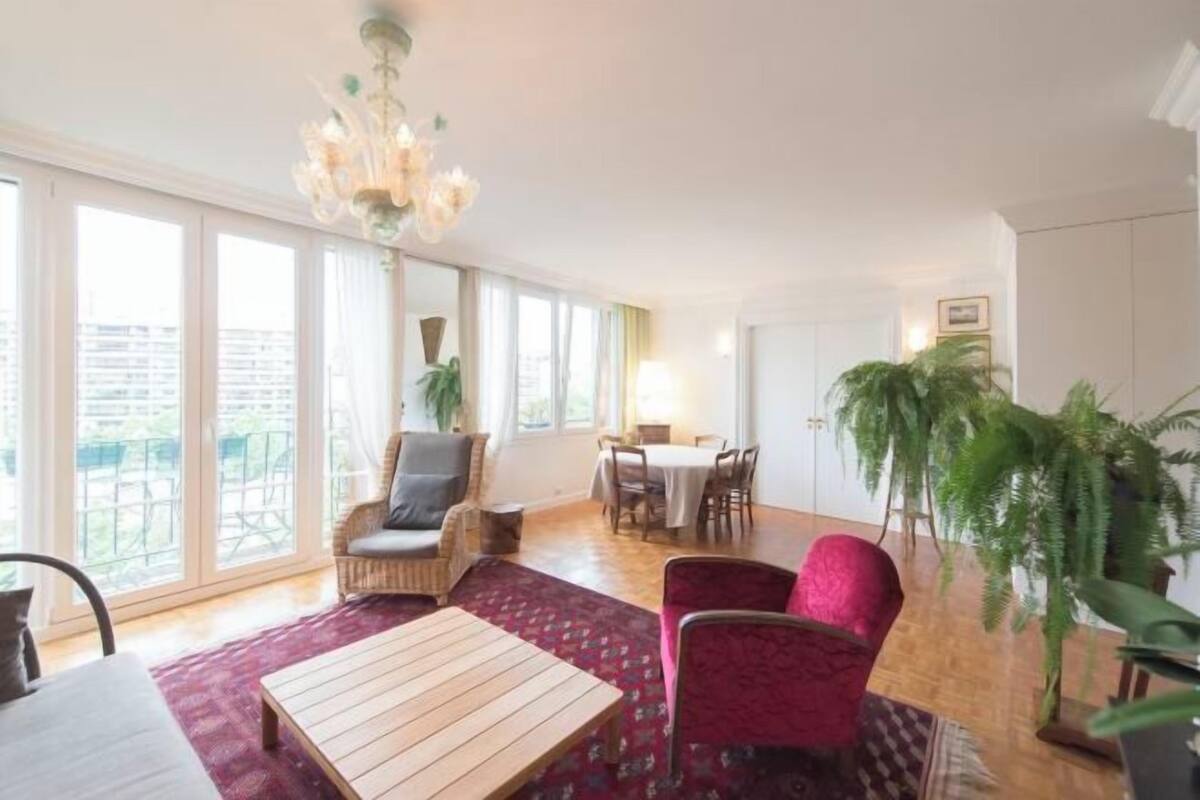 Een ruime kamer met een groot raam, een eethoek en een zithoek met een tafel en stoelen.