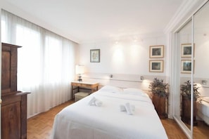 Una habitación de hotel con una cama grande, un escritorio de madera, una silla y un espejo.